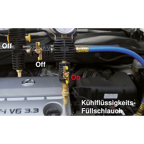 Nahaufnahme eines Motors, an dem ein Kühlflüssigkeits-Füllschlauch und Messgeräte angeschlossen sind. Auf einem Ventil steht „On“. Im Hintergrund ist ein Auto zu sehen.